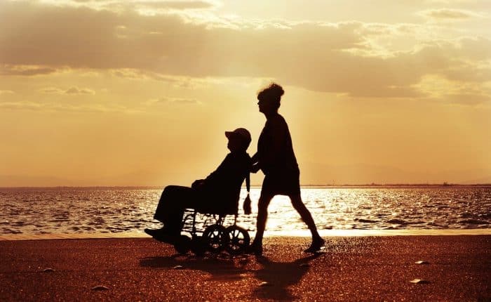 woman pushing man in a wheelchair on the beach