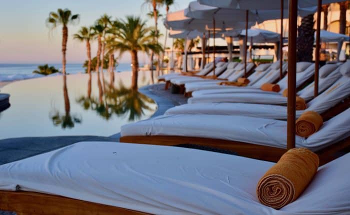 row of lounge chairs with palm trees in the distance