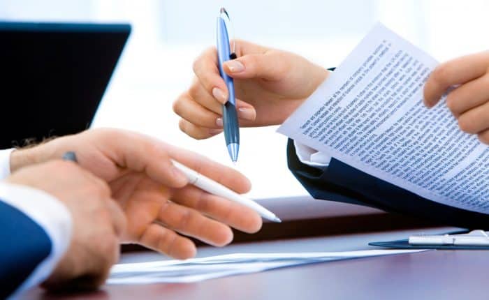 two people holding pens discussing a contract