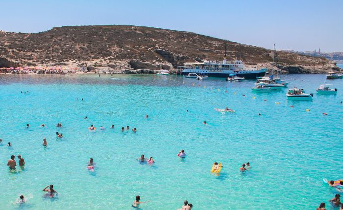 people in the sparkling blue sea with land in the distance