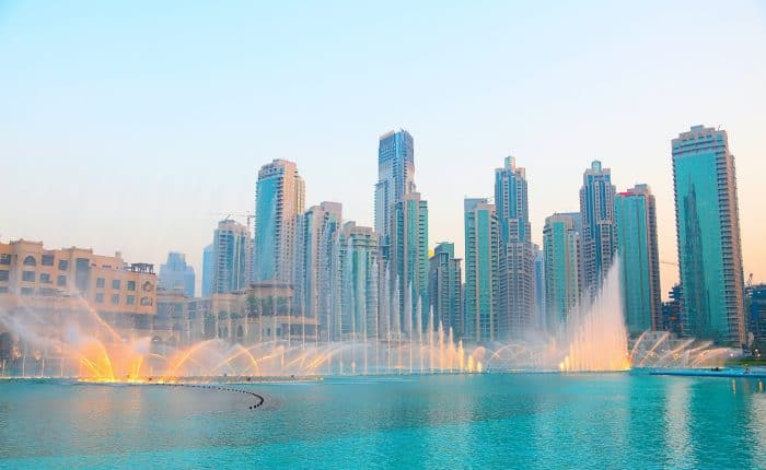 fountains in a beautiful pool with highrise buildings behind