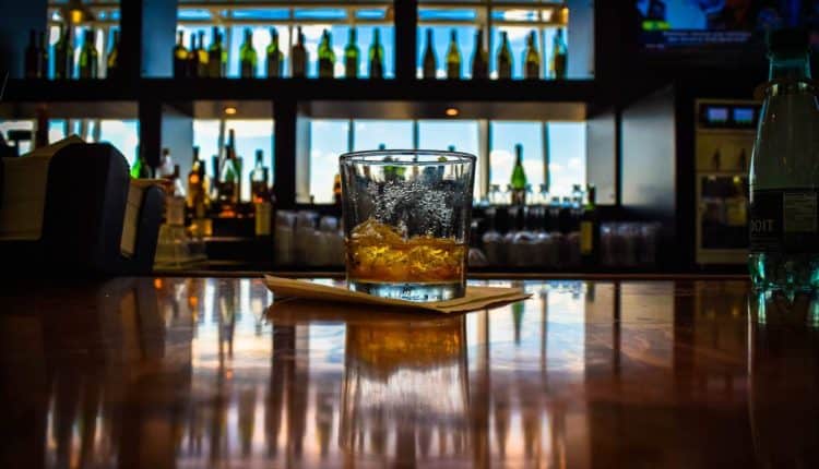 A glass of whiskey on the rocks on a wooden bar