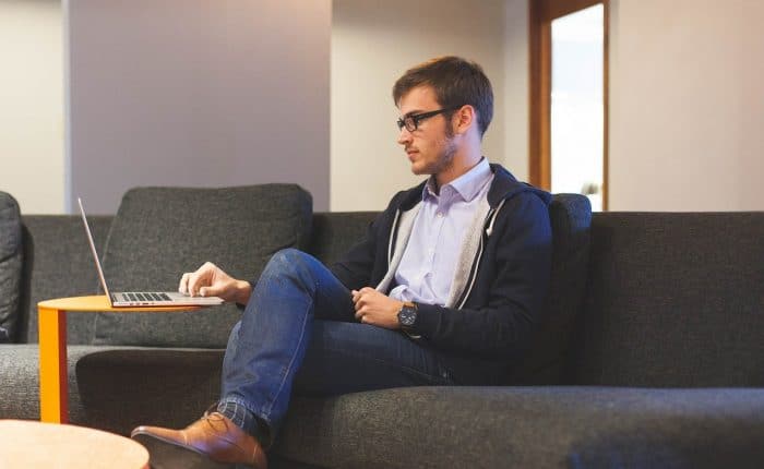 Entrepreneur filing his taxes on his laptop while he sits on a couch
