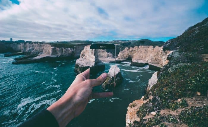 Hand with phone overlooking water