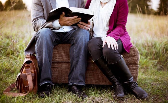 couple reading a book on a couch outside