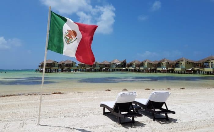two lounge chairs on the beach with a Mexican Flag