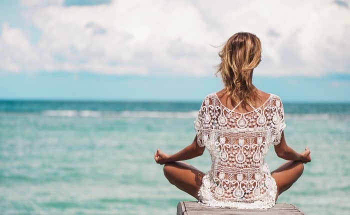 Woman sitting on a deck looking out to the ocean