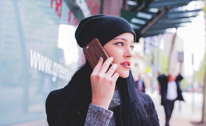 girl holding mobile phone with dark whool hat on